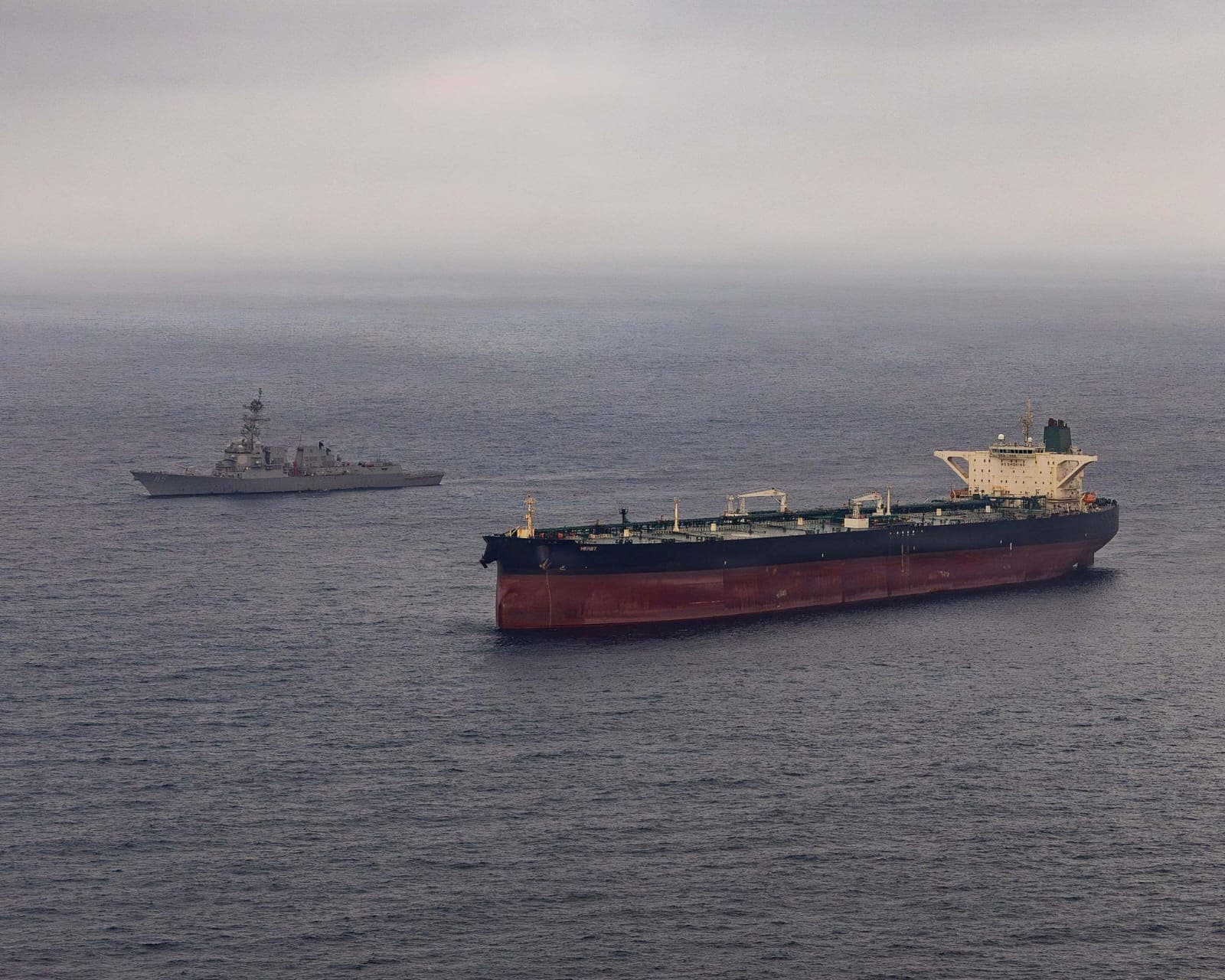 Military ships escorting oil tankers in the Strait of Hormuz during US Iran War